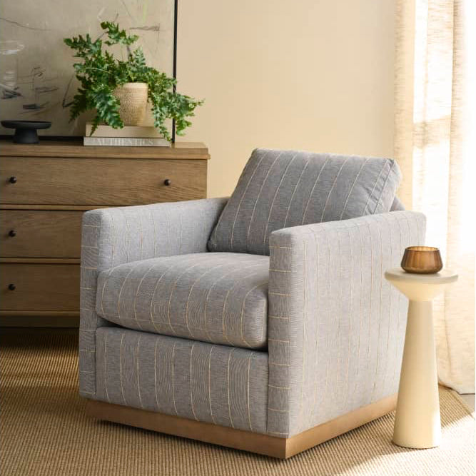 Gray armchair in a room with a dresser, plant, and side table.