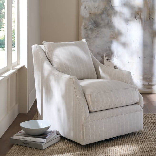 Beige armchair in a room with large windows and a textured wall.