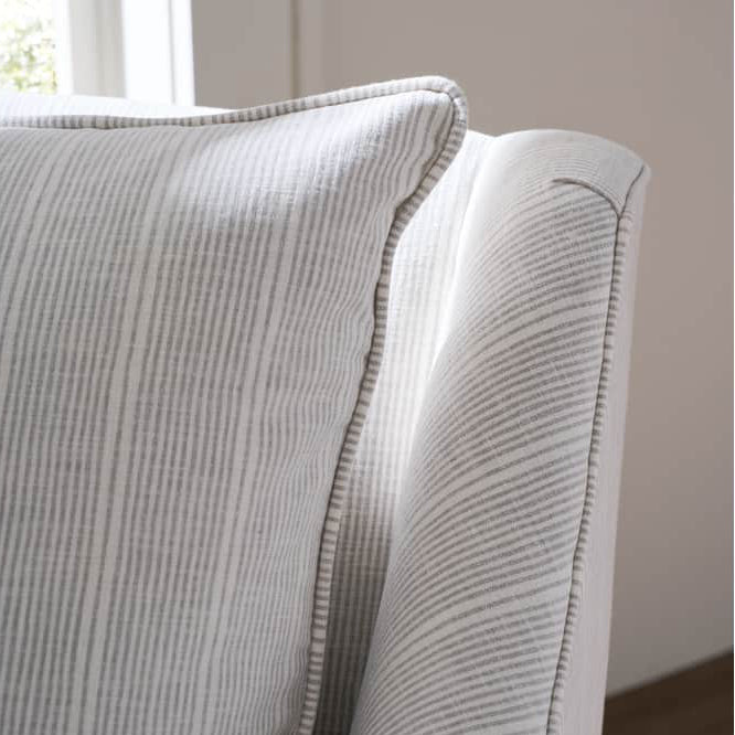 Close-up of a textured gray pillow on a chair with a neutral background