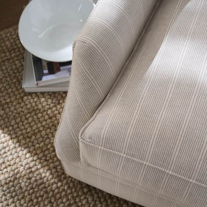 Beige textured sofa corner with a white bowl on a small table in the background.