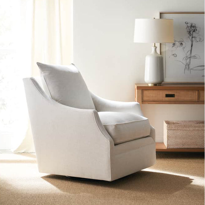 White armchair in a bright room with light-colored walls and a small table with a lamp.