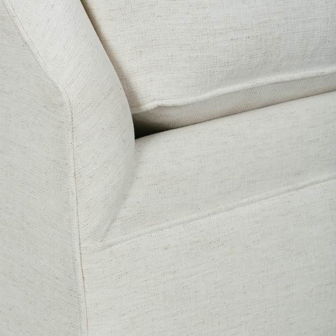 Close-up of a light beige textured fabric upholstered furniture corner with a matching cushion, shown on a white background.