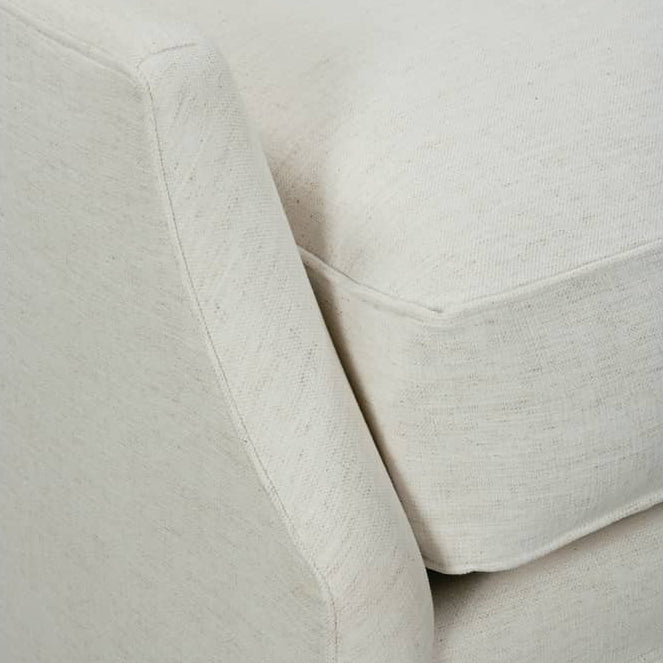 Close-up of a light beige upholstered armchair showing the fabric texture, seat cushion, and armrest.