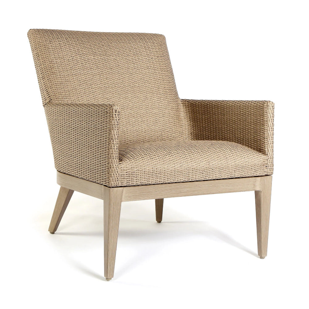 A modern outdoor armchair with a woven beige wicker or rattan seat and back, supported by a light gray wooden frame with angled legs, shown on a white background.