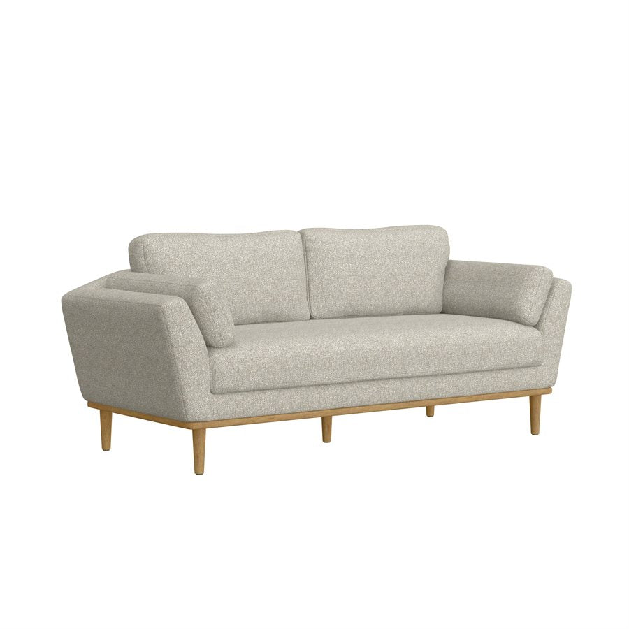 A beige chenille fabric sofa with wide angled arms, plush pillows, a brown exposed solid wood frame, and modern tapered legs.